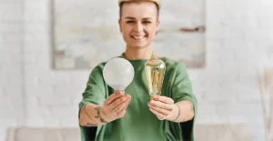 Smiling person holding two different light bulbs—symbolizing choice, insight, and the discovery of new perspectives in the recovery journey at the rehab center.